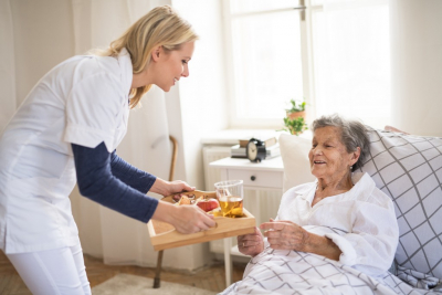 woman giving food to senior woman